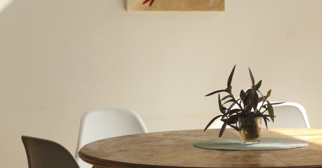Sunlit minimalist dining room with round table, chairs, and painting.